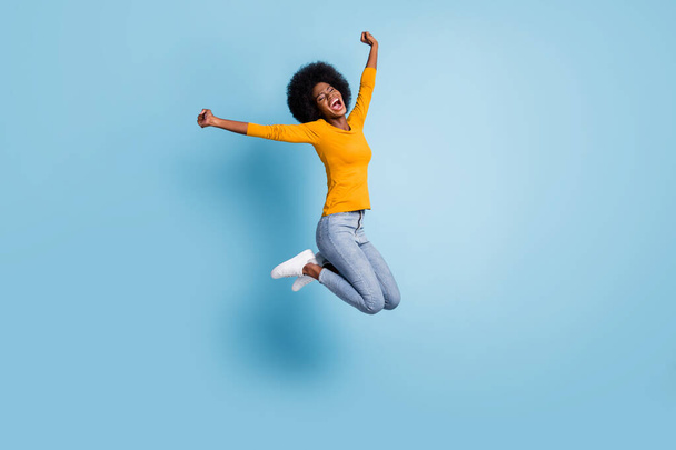Photo portrait full body of excited girl celebrating jumping up isolated on pastel blue colored background - Foto, afbeelding
