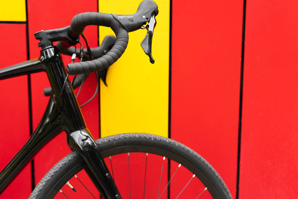 Primo piano di una bicicletta in metallo nero vicino a un muro luminoso. Attrezzature sportive. - Foto, immagini