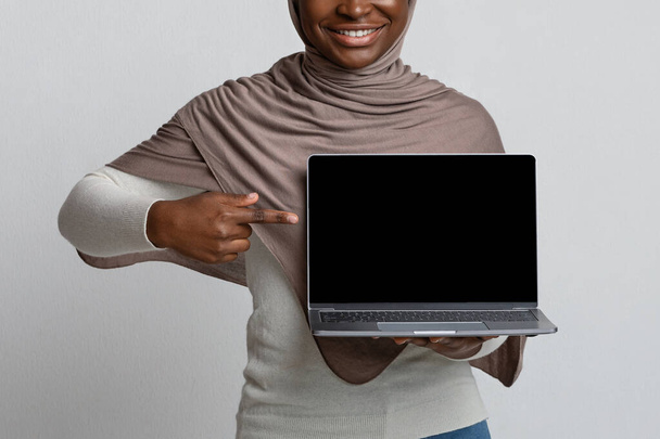 Donna africana in Hijab che indica al computer portatile con lo schermo nero, immagine di Mockup - Foto, immagini