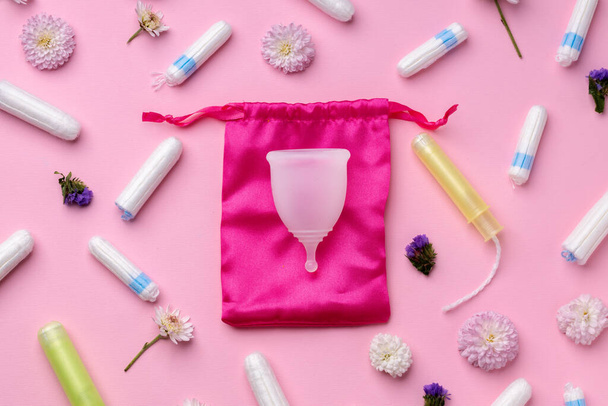 Menstrual cup and tampons on floral pattern background - Foto, Imagen