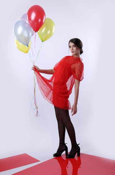 Girls in a red dress and black tights with balloons on a light background - Fotoğraf, Görsel
