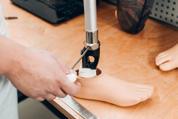Technician checking artificial limb while at desk in workshop, adjusting it and checking for quality. the latest prosthetic technologies - Photo, Image