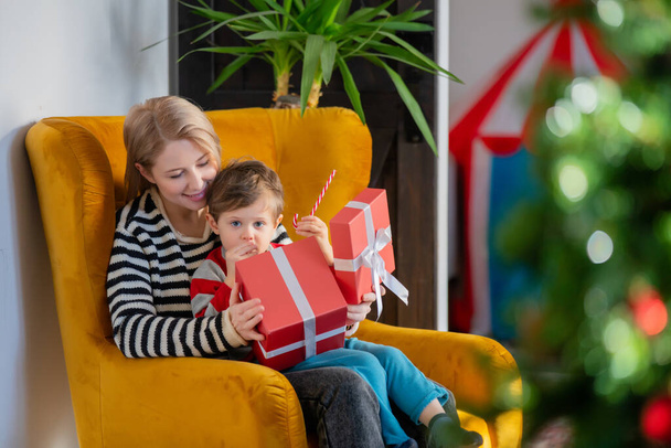 mom and son are sitting in a armchair with a gift - Photo, image