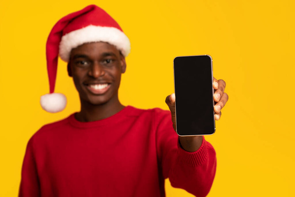 Mockup di ragazzo africano in Santa Hat Holding Smartphone con schermo nero - Foto, immagini