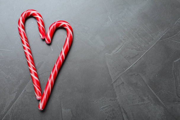 Heart made of Christmas candy canes on grey background, flat lay. Space for text - Foto, immagini