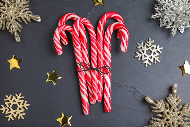 Sweet candy canes and Christmas decor on black background, flat lay - Fotó, kép