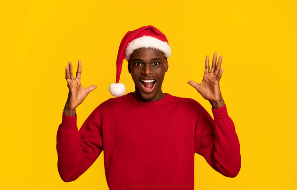 Christmas Offer. Shocked Black Man In Santa Hat Raising Hands In Excitement - Фото, изображение