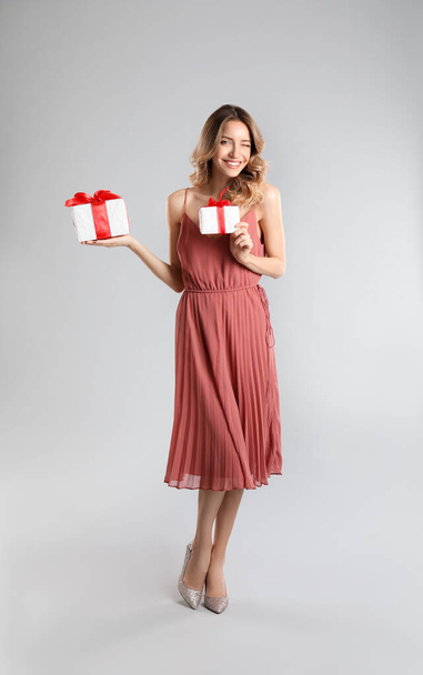 Beautiful young woman with Christmas presents on light grey background - Φωτογραφία, εικόνα