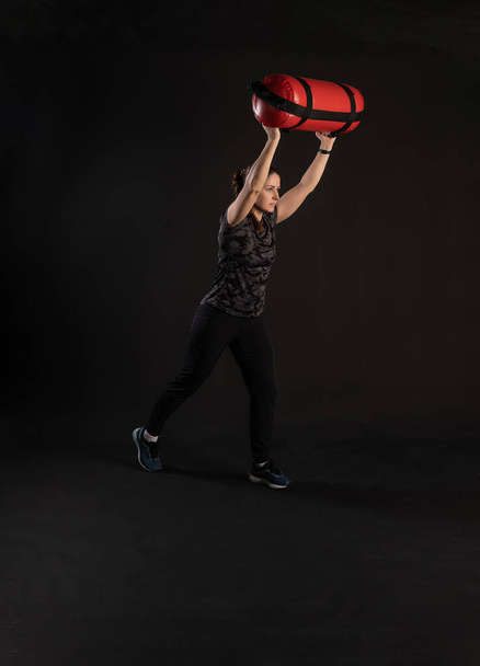 Fitness c Aqua Bag, picks up does exercises. Engaged in Sports on a Black Background Smiling smiles at the camera - Photo, image
