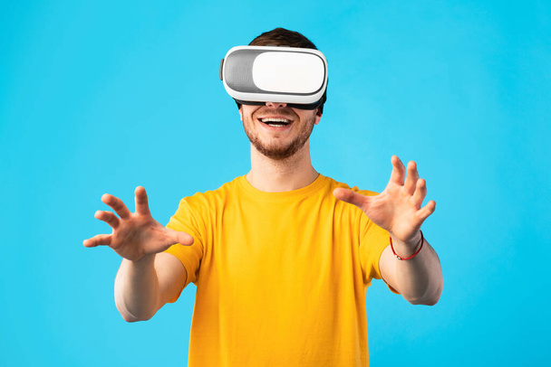 Hombre sonriente con auriculares de realidad virtual en el estudio - Foto, Imagen