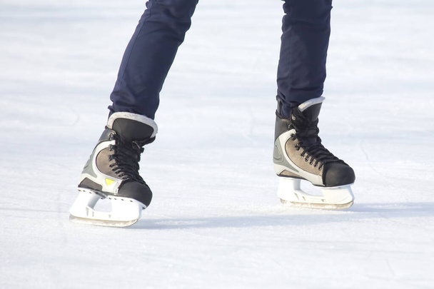 Πόδια ενός άντρα που κάνει πατινάζ σε παγοδρόμιο. Χόμπι και σπορ. Διακοπές και χειμερινές δραστηριότητες - Φωτογραφία, εικόνα