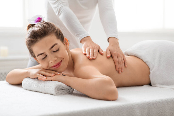 Mujer pacífica disfrutando de masaje de espalda en el spa - Foto, Imagen