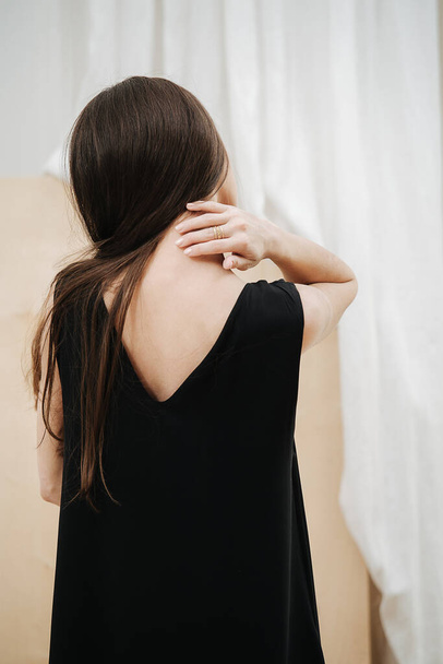 Sensual young beautiful woman wearing a black V-neck dress. View from behind. - Fotó, kép