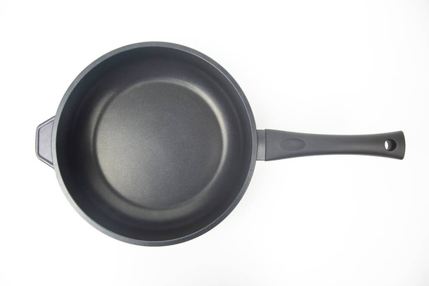 Чорна сковорода з антипригарним покриттям тефлону на білому фоні
 - Фото, зображення