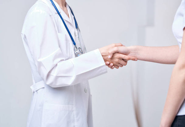 Médico y paciente se dan la mano el uno al otro en un fondo claro recortado vista - Foto, imagen