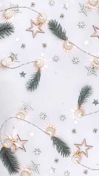 Weihnachtskomposition aus hölzernen Sternen, einem Kranz aus weißen leuchtenden Kugeln, Tannenzweigen, Glocken und Schneeflocken auf weißem Hintergrund - Foto, Bild