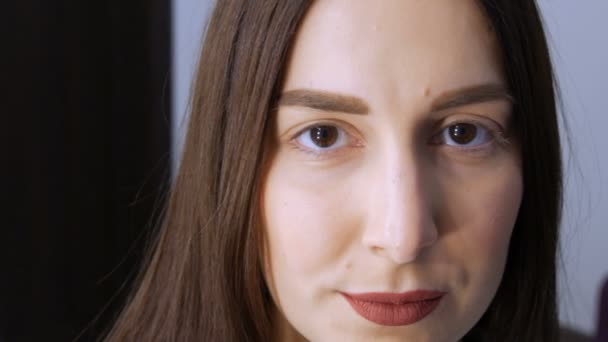 Het gezicht van een jong meisje voor een moderne wimper lamineren procedure in een professionele schoonheidssalon voor de wimper curling procedure. Portret van een vrouw zonder make-up met donkere lippenstift - Video