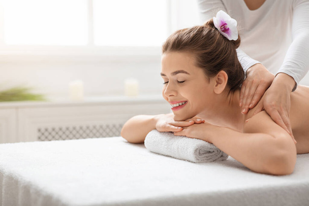 Radosna młoda kobieta korzystająca z masażu pleców w spa - Zdjęcie, obraz