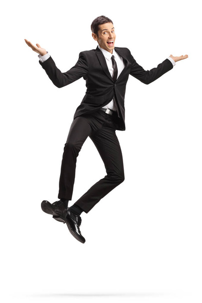 Excited young businessman in suit and tie jumping isolated on white background - Foto, afbeelding