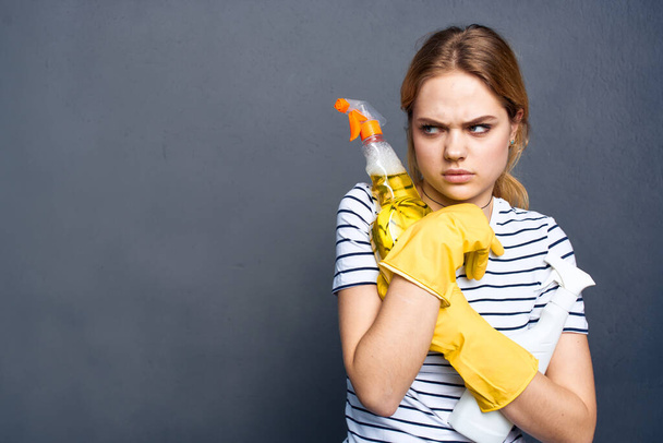 Žena drží saponát v rukou úklid domácí práce životní styl šedé pozadí - Fotografie, Obrázek