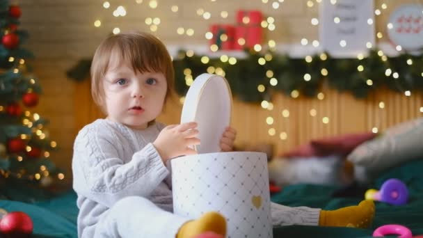Das Kind öffnet ein Weihnachtsgeschenk. Glückliche Kindheit. Frohe Weihnachten. Warten auf die Magie. - Filmmaterial, Video