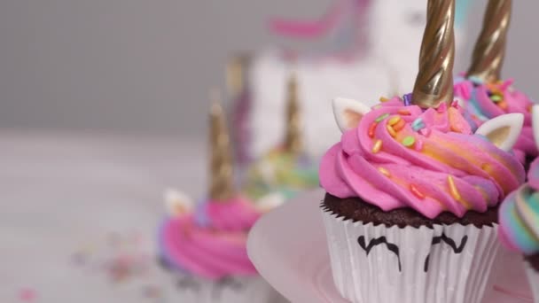 Pastelitos de unicornio decorados con glaseado de crema de mantequilla colorida y espolvoreos. - Metraje, vídeo