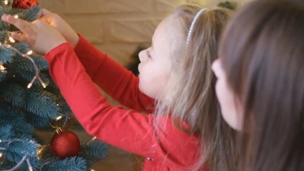 Anya és lánya együtt díszítik a karácsonyfát. Hagyományos nevelés. - Felvétel, videó