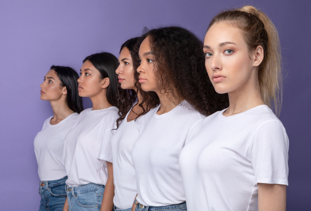 Группа серьезных мультикультурных женщин, стоящих в ряд, фиолетовый фон - Фото, изображение