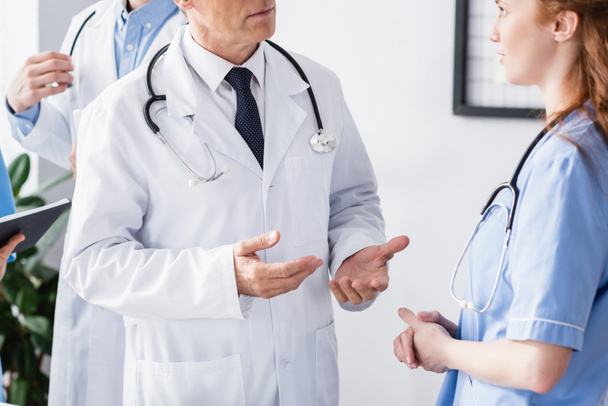 Doctor with stethoscope talking to nurse in hospital  - Zdjęcie, obraz