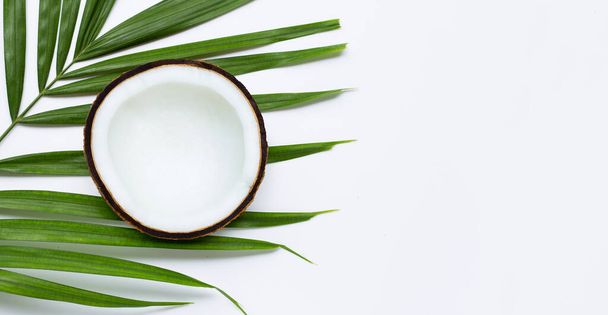 Half coconut on tropical palm leaves on white background. Top view - 写真・画像