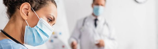 African american nurse in medical mask near doctor on blurred background in hospital, banner  - Photo, Image