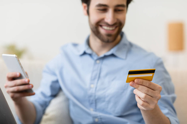 スマートフォンやクレジットカードのオンラインショッピングで幸せな男屋内 - 写真・画像