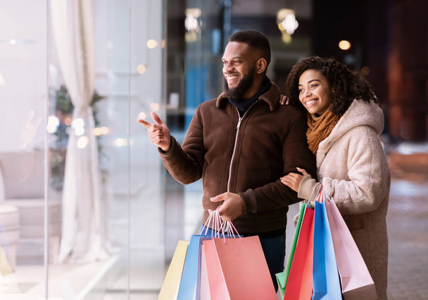 Retrato de feliz pareja negra con bolsas de compras caminando - Foto, imagen