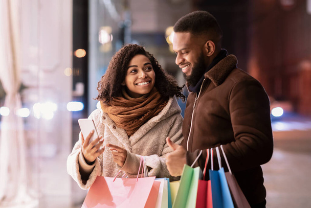 Felice coppia afro utilizzando smartphone con shopping bags - Foto, immagini