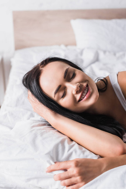 smiling young brunette woman in bed - Fotoğraf, Görsel