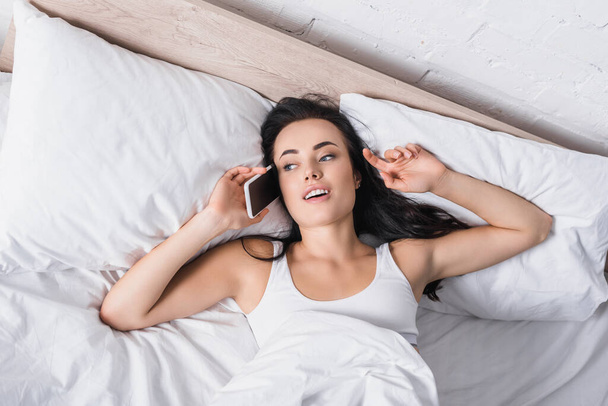 jovem morena mulher falando no smartphone na cama - Foto, Imagem
