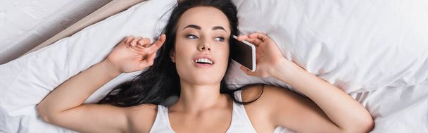 jeune femme brune parlant sur smartphone au lit, bannière - Photo, image