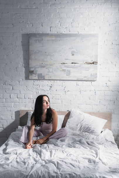 Nuori brunette nainen istuu sängyssä aamulla - Valokuva, kuva