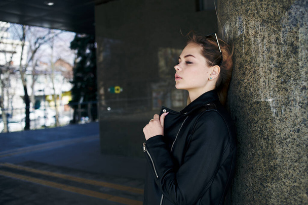 kobieta w skórzanej kurtce na ulicy w mieście i okulary przeciwsłoneczne edycji w tle - Zdjęcie, obraz