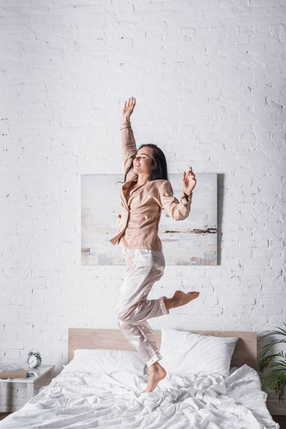 young brunette woman jumping in bed at morning - Photo, Image