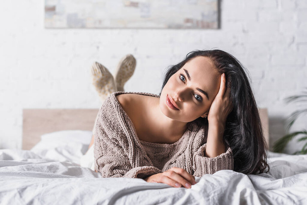 young brunette woman in sweater lying in bed at morning - Foto, Imagem
