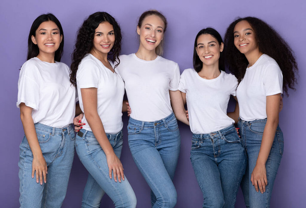 Vijf vrolijke diverse dames poseren omhelzend en glimlachend, paarse achtergrond - Foto, afbeelding