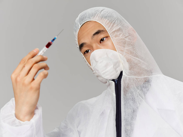 Άντρας αμυντικός φορώντας ιατρικά ρούχα μια σύριγγα στα χέρια ενός εμβολίου υγείας κοντινό πλάνο - Φωτογραφία, εικόνα