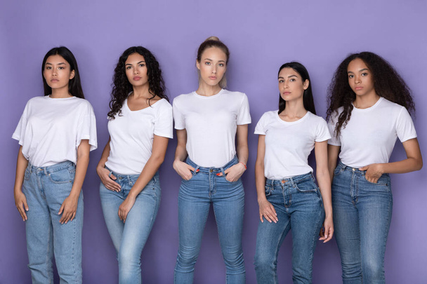 Пять серьезных мультикультурных дам, стоящих вместе на фиолетовом фоне - Фото, изображение