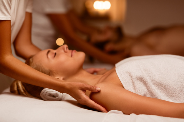 Vrouw en echtgenoot genietend van ontspannen massage liggend in luxe spa - Foto, afbeelding