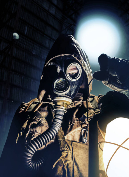 Stalker πολεμιστής σε προστατευτική σοβιετική μάσκα αερίου κρατώντας φανάρι βενζίνης σε νυχτερινές σήραγγες. - Φωτογραφία, εικόνα
