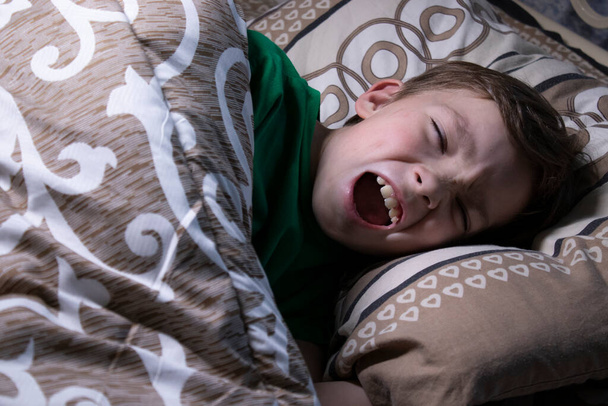 portré egy kilenc éves szőke fiúról az ágyban. - Fotó, kép