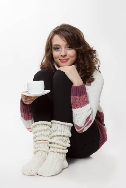Joven morena sosteniendo taza de té caliente sobre fondo blanco. - Foto, imagen