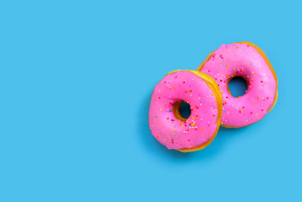 Vaaleanpunaisia donitseja sinisellä taustalla. Yläkuva - Valokuva, kuva
