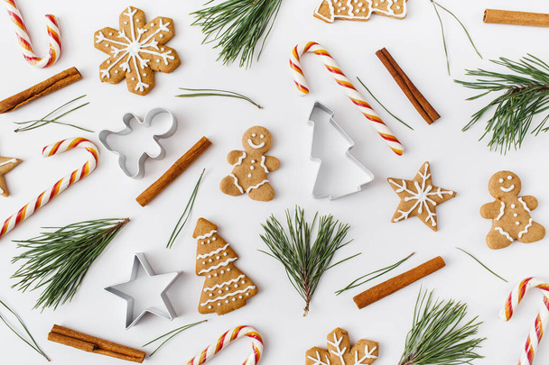 Christmas, winter, new year composition. Pattern made of Fir tree branches, cinnamon sticks, candies, gingerbread on white background. Flat lay, top view - Photo, image